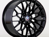 A black, multi-spoke alloy wheel with a BMW logo at the center is displayed against a plain white background.