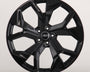 A glossy black alloy wheel with a multi-spoke design. The Audi logo is centered on the hub. It's set against a plain, light grey background.