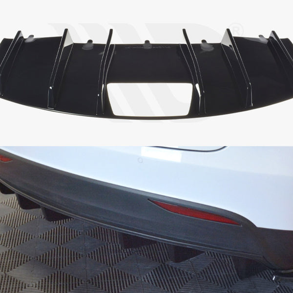 A black vehicular rear diffuser with vertical fins is shown, designed for aerodynamic purposes. It is intended to be installed on a white car's rear bumper, seen parked on a textured floor.