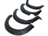 Four black fender flares are arranged on a white background, displaying segments with bolt details and smooth curves, typically used for automotive customization and protection.