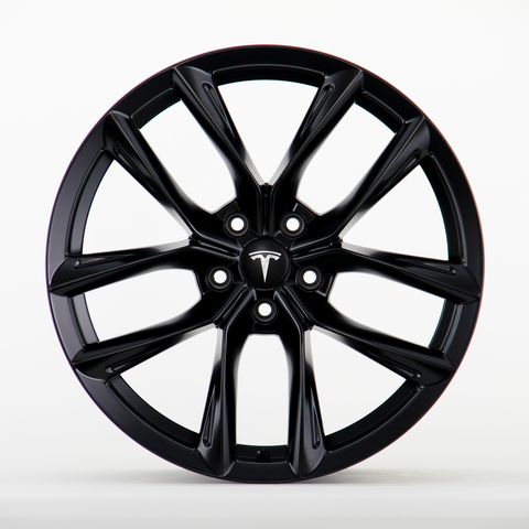 A black wheel rim featuring a sleek, multi-spoke design with the Tesla logo visible at the center, placed against a plain white background.
