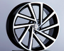 A stylish black and silver alloy wheel, featuring the Volkswagen logo, is displayed upright on a dark stand against a plain gray background.