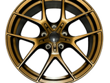 A bronze alloy wheel with a multi-spoke design is centered against a plain white background, highlighting its intricate pattern and sleek finish.