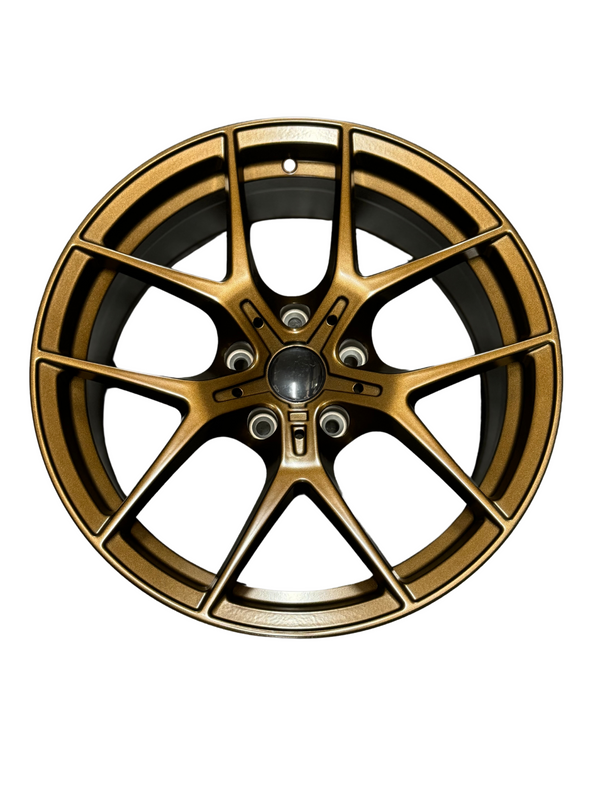 A bronze alloy wheel with a multi-spoke design is centered against a plain white background, highlighting its intricate pattern and sleek finish.