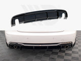 A black car rear diffuser lies above the image of a white car's rear bumper featuring dual exhaust pipes and a checkered floor beneath.