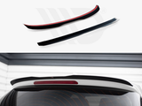 Two black car spoilers rest on a white background, displayed above a white vehicle rear window. The vehicle features a red brake light, set within a garage-like space.