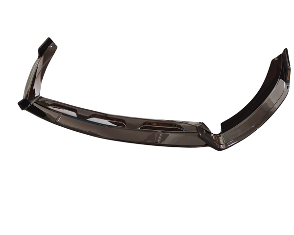 A glossy, metallic car bumper component is angled upward, reflecting light. It features several rectangular cutouts and is set against a plain white background.