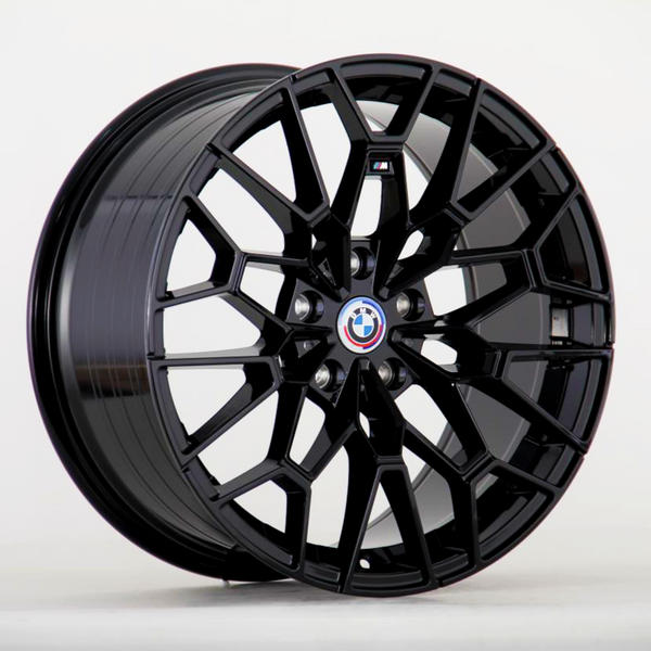 A black, multi-spoke alloy wheel featuring a BMW logo at the center, positioned against a plain white background. The intricate spokes create geometric patterns, highlighting a modern design.