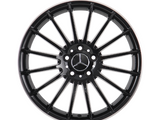 A black alloy wheel with a multi-spoke design features a central Mercedes-Benz logo. It is isolated on a white background, highlighting its sleek, symmetrical structure.