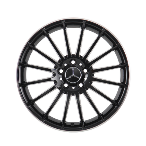 A black alloy wheel with a multi-spoke design features a central Mercedes-Benz logo. It is isolated on a white background, highlighting its sleek, symmetrical structure.