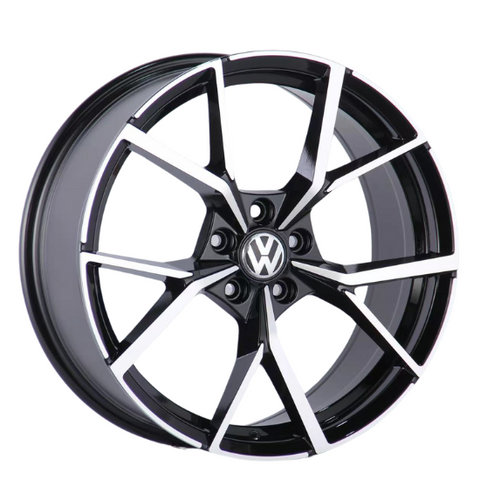 A black and silver alloy wheel with a geometric pattern, displaying the Volkswagen logo in the center, is positioned against a plain white background.