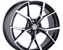 A black and silver alloy wheel with a geometric pattern, displaying the Volkswagen logo in the center, is positioned against a plain white background.