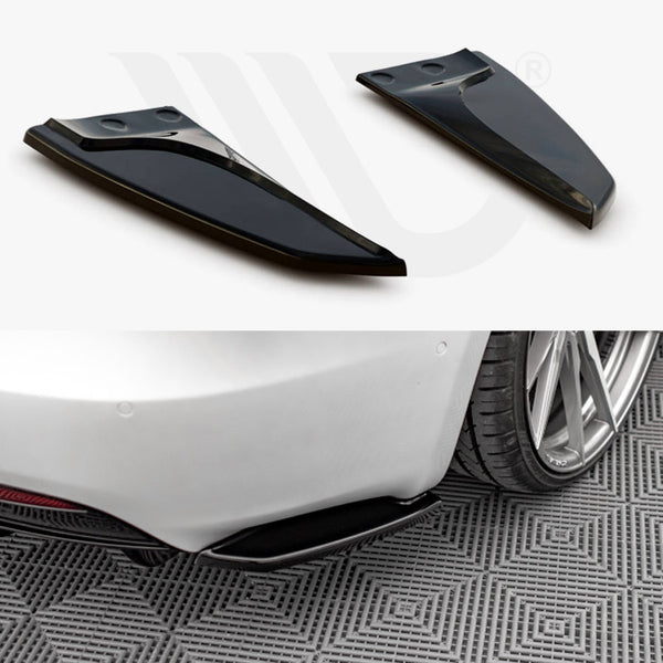 Two black aerodynamic fins positioned above, shown detached; below, they are installed on the rear of a white car, parked on patterned flooring, near a rear wheel.