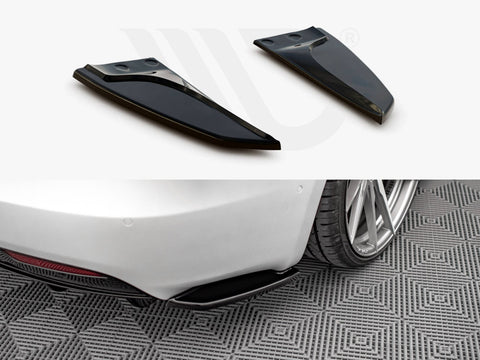 Two black aerodynamic fins positioned above, shown detached; below, they are installed on the rear of a white car, parked on patterned flooring, near a rear wheel.