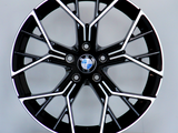 A black and silver BMW alloy wheel, featuring a multi-spoke design, is displayed upright on a light gray circular platform. The BMW logo is centered.