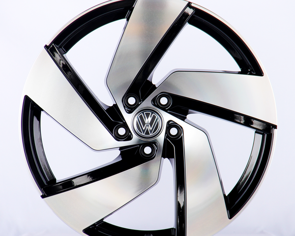 A metallic car wheel with a five-spoke design featuring a central logo; it rests against a plain white background.
