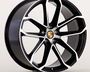 A black and silver alloy wheel features the Porsche emblem at the center, with a modern, multi-spoke design. The wheel is set against a plain, light background.