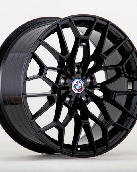 A black alloy wheel showcases a geometric, multi-spoke design, prominently featuring a BMW logo at its center against a plain, light gray background.