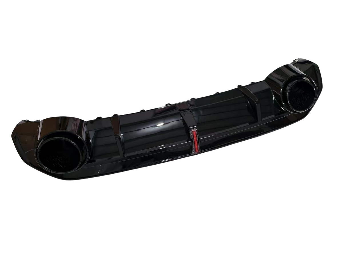 A glossy black car rear diffuser, featuring dual circular exhaust ports, lies isolated against a white background. The central section has vertical fins, enhancing aerodynamics.