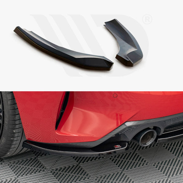 Two black car parts on a white background; below, one part is attached near the rear wheel and exhaust of a red car with black wheels on a patterned floor.