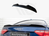 A black car spoiler is displayed above a blue Audi A5, enhancing aerodynamics. The rear of the car, parked indoors, shows taillights and badges. Text: 