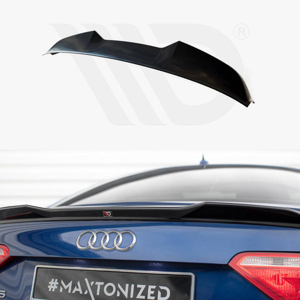 A black car spoiler is displayed above a blue Audi A5, enhancing aerodynamics. The rear of the car, parked indoors, shows taillights and badges. Text: "#MAXTONIZED."