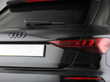A black Audi car's rear showcases its logo and taillights. The vehicle is stationary, possibly in a studio setting with a neutral background.