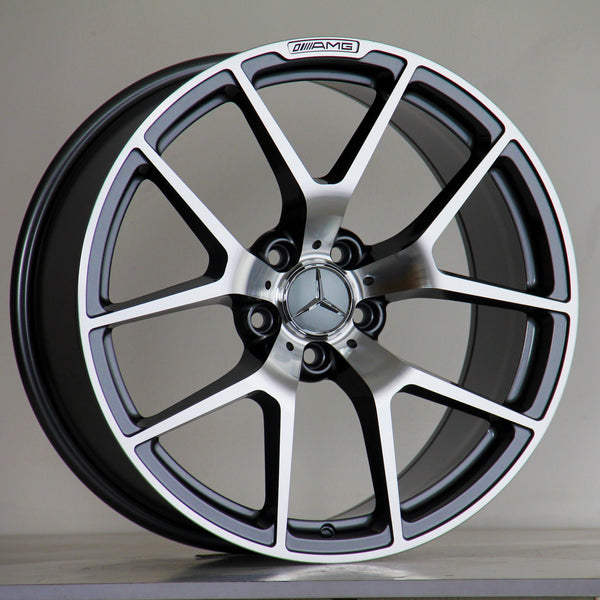A Mercedes-Benz alloy wheel stands upright, featuring a five-spoke design with a polished finish. The AMG logo is inscribed at the top. It's set against a neutral background.
