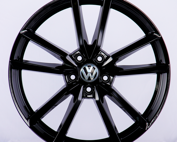 A glossy black car wheel rim with a Volkswagen logo at the center, featuring a split-spoke design, displayed against a plain white background.