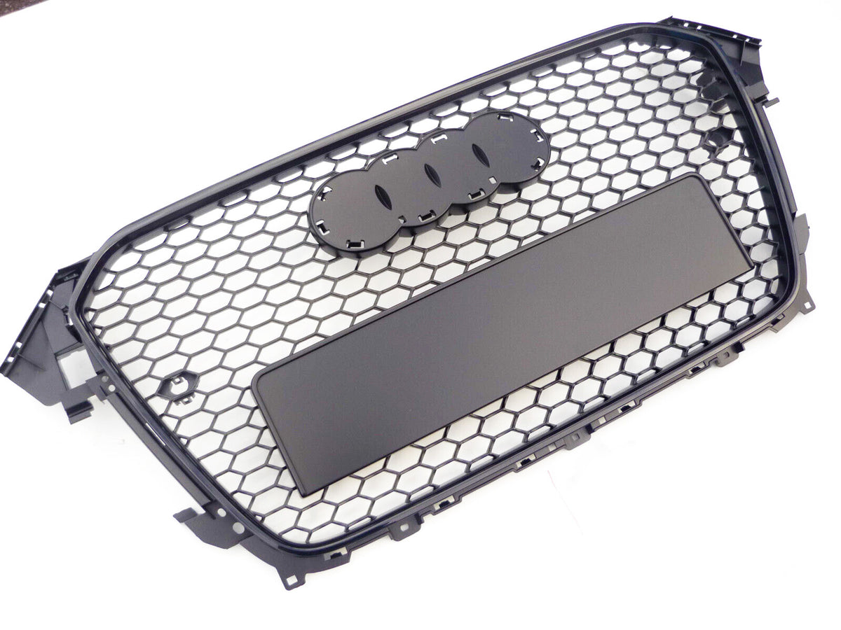 A black, hexagonal-patterned car grille with spaces for emblem attachment lies against a plain white background.