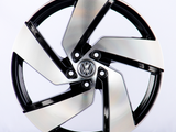 A metallic car wheel rim with a five-spoke design features a central logo containing a 