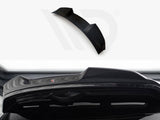 A black car spoiler, designed for aerodynamics, is positioned against a white background with branding visible. Its sleek design complements the rear of a vehicle, enhancing performance aesthetics.