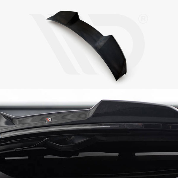 A black car spoiler, designed for aerodynamics, is positioned against a white background with branding visible. Its sleek design complements the rear of a vehicle, enhancing performance aesthetics.
