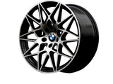 A sleek, intricate multi-spoke BMW car wheel with a central blue and white logo is displayed against a plain white background, emphasizing its geometric design and smooth finish.