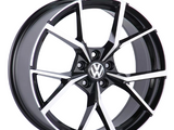 A black and silver alloy wheel with the Volkswagen logo at the center. The wheel's angular spoke design appears sleek and modern, set against a plain white background.