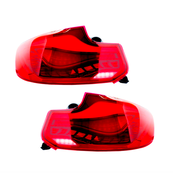 Two red car taillights, unlit, are displayed against a plain white background. Each taillight features intricate internal details and black mounting connectors.