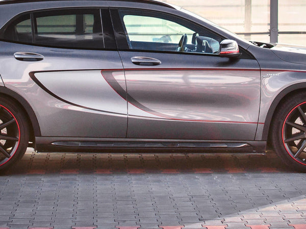 A gray car with red accented wheels is parked on a patterned pavement. The vehicle's side features a bold contour design and visible text "X2 ARTE" near the front wheel.
