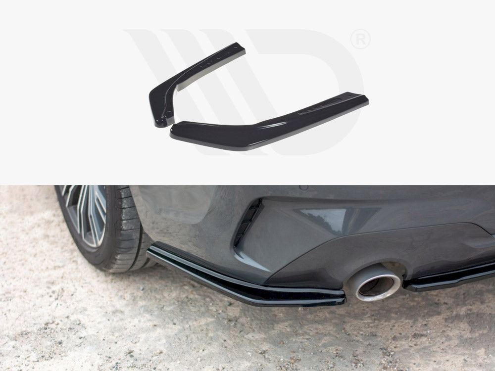 Two black car rear spoilers are displayed above an image showing them installed on a gray car's rear bumper next to the exhaust pipe, on a gravel surface.