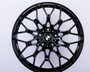A black, intricately designed car wheel rim with the BMW logo at the center against a plain white background.