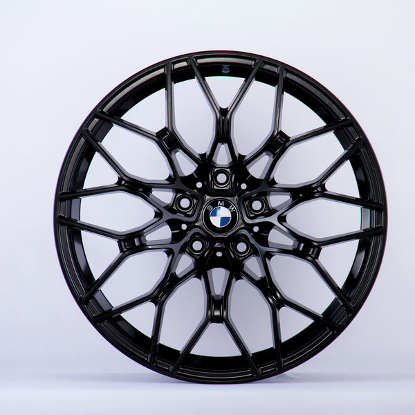 A black, intricately designed car wheel rim with the BMW logo at the center against a plain white background.