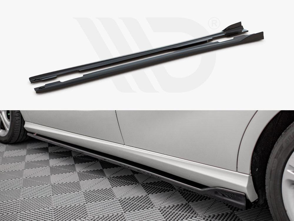 Two black side skirts are displayed individually and attached to the side of a silver car, enhancing its appearance on a checkered garage floor.