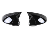 Two black, glossy side mirrors with aerodynamic design sit facing each other against a plain white background, reflecting light and showing smooth surface contours.