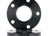 A metallic, round flange with five evenly spaced holes rests on a similar base. The objects are black, featuring a smooth, polished surface. Background is plain white.