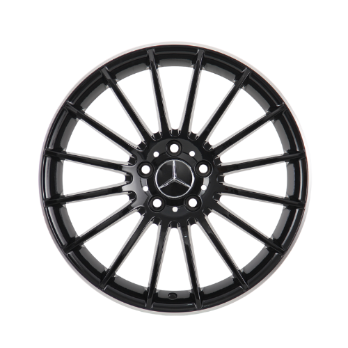 A black alloy wheel with multiple spokes featuring a central emblem resembling interlocking triangles; it is isolated on a white background, showcasing its symmetrical design.