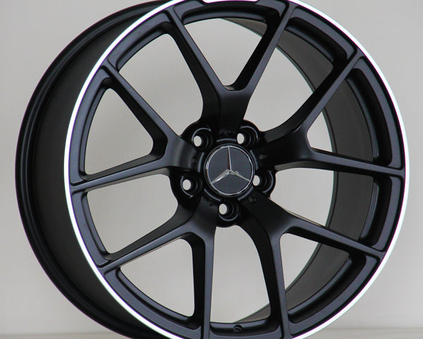 A black alloy wheel with a five-spoke design, featuring a Mercedes-Benz logo in the center and "AMG" text on the rim, rests against a simple, plain background.