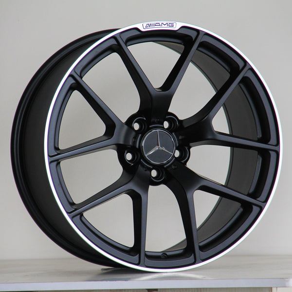 A black alloy wheel with a five-spoke design, featuring a Mercedes-Benz logo in the center and "AMG" text on the rim, rests against a simple, plain background.