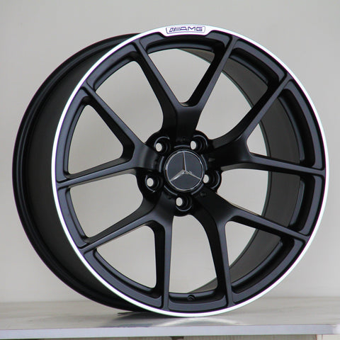 A black alloy wheel with a five-spoke design, featuring a Mercedes-Benz logo in the center and "AMG" text on the rim, rests against a simple, plain background.