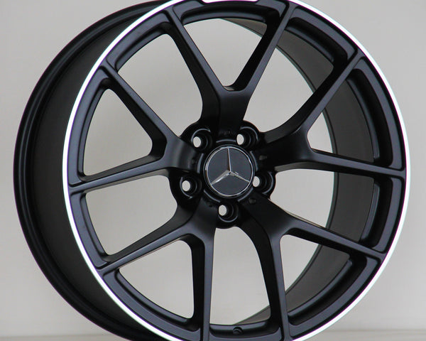 A black alloy wheel with a silver Mercedes logo, features the text "AMG" above the rim. It rests on a light surface against a plain background.