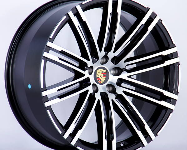 A black and silver alloy wheel with a multi-spoke design featuring the Porsche logo at the center, displayed against a plain white background.