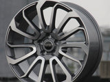 A polished silver and black alloy wheel rests upright on concrete. 